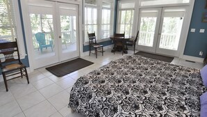 Une chambre avec un grand lit, une chaise, un bureau et une vue sur l’extérieur grâce à une porte coulissante.