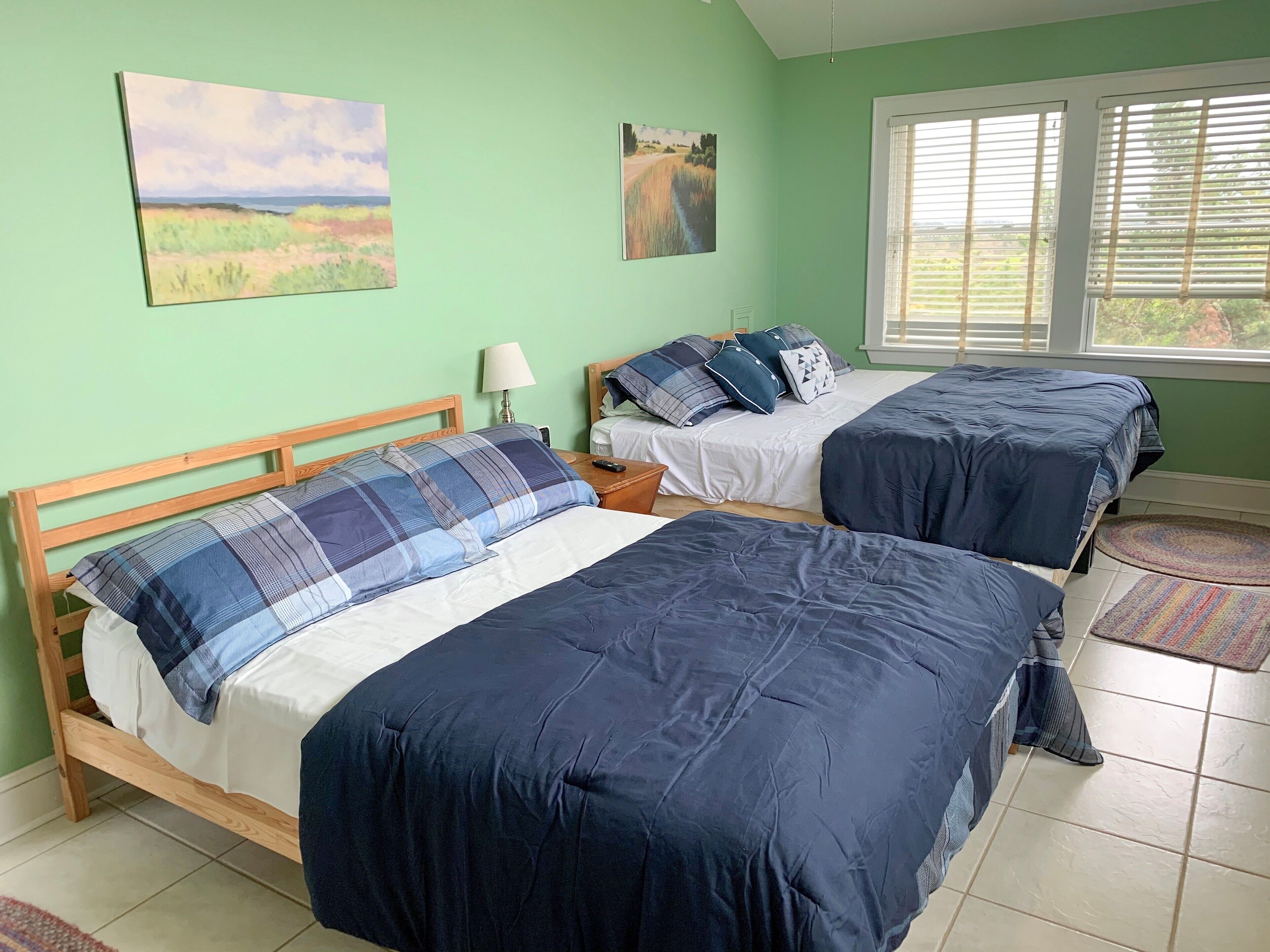 A room with two beds, a lamp, and artwork on the walls.
