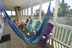 A covered porch with a hammock, colorful Adirondack chairs, and a wooden ladder. - Starry Night: Unobstructed marsh views from the screened porch. (Ocracoke)