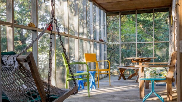 A wooden deck with a hammock, chairs, and a table. - Lindley:  Near restaurants, spacious screened porch, rooftop deck. (Ocracoke)