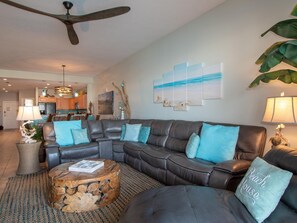 A modern living room with a sectional sofa, a wooden coffee table, and a ceiling fan.