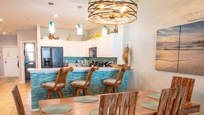 Una cocina moderna con salpicadero azul, sillas de madera y una mesa de comedor.