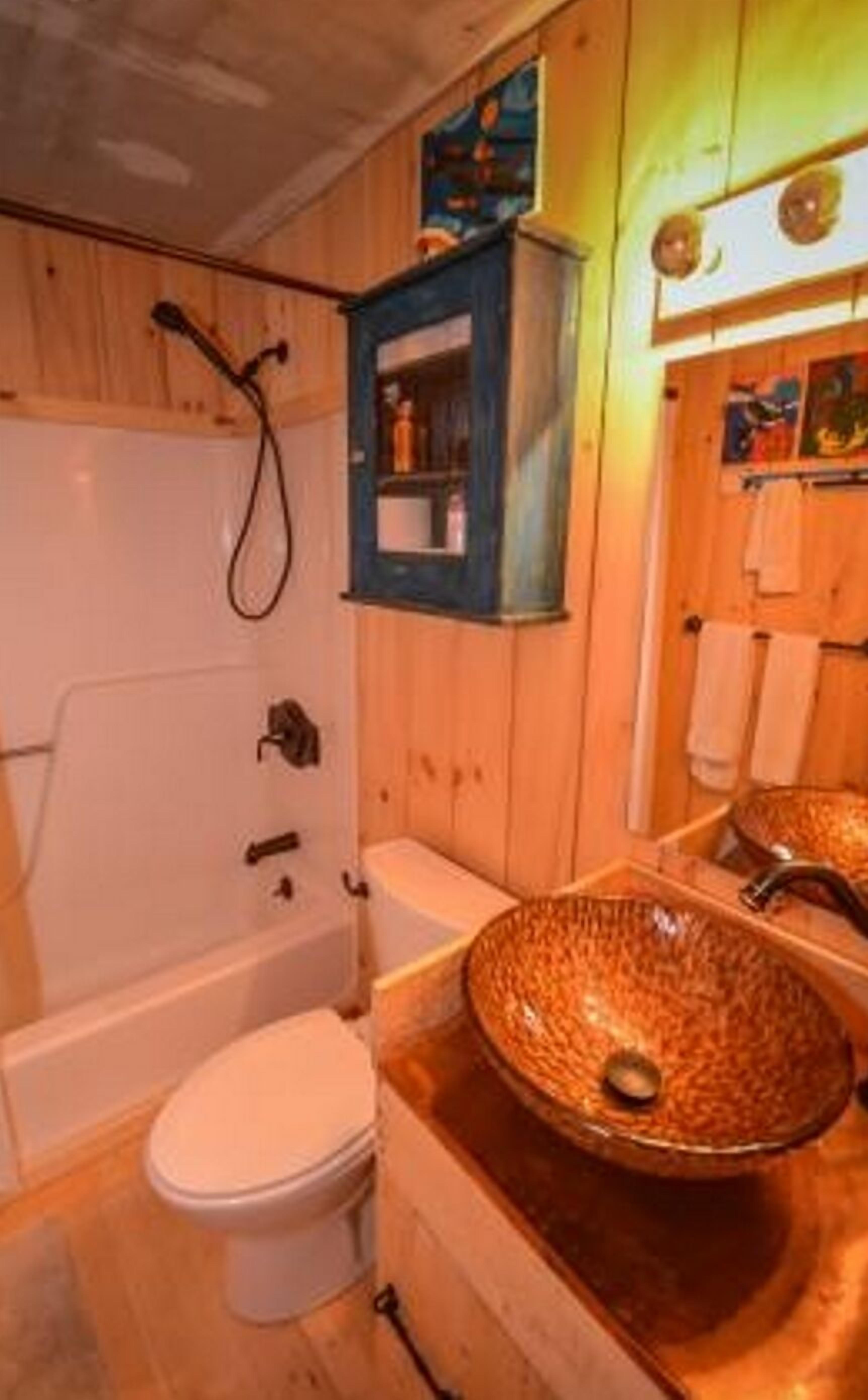 Een houten badkamer met een badkuip, toilet en een grote wastafel.