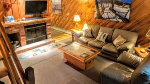 Ein gemütliches Wohnzimmer mit Kamin, Ledersofa und Wandfernseher.