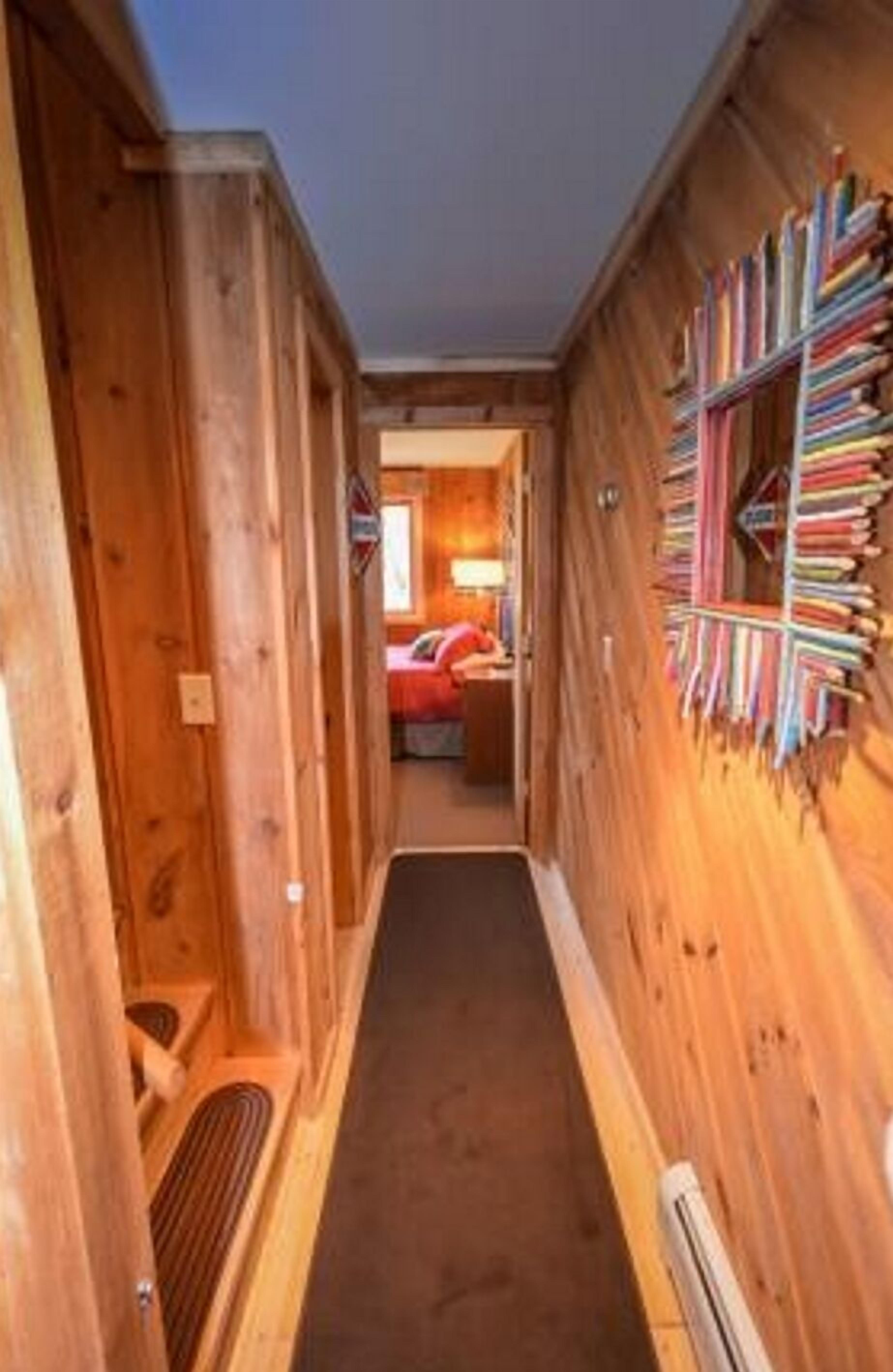 A wooden hallway with a carpeted floor, a radiator, and a bookshelf filled with books.
