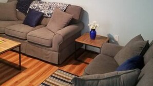 Ein Wohnzimmer mit einer braunen Couch, einem Couchtisch und einem Streifenmuster-Teppich.