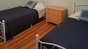 Ein Schlafzimmer mit zwei Einzelbetten, einem Holzschrank und einer Deckenleuchte.