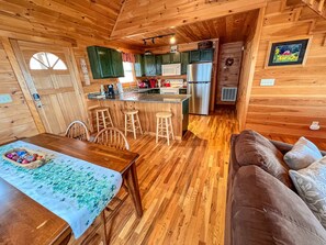 Una cocina acogedora de estilo rústico con pisos de madera, un comedor con mesa y sillas, y una kitchenette con refrigerador y microondas.