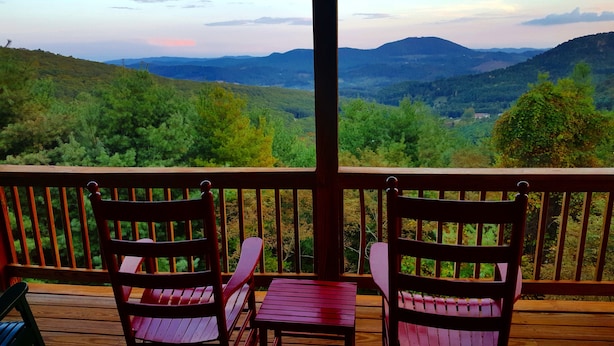 A wooden deck with two chairs and a small table, overlooking a mountainous landscape. - Absolute High | 3BR Cabin w/ Long-Range Mountain Views, Game Room & Deck (West Jefferson)
