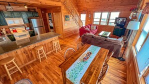 A wooden cabin interior with a kitchen, dining area, and living room. - Absolute High | 3BR Cabin w/ Long-Range Mountain Views, Game Room & Deck (West Jefferson)