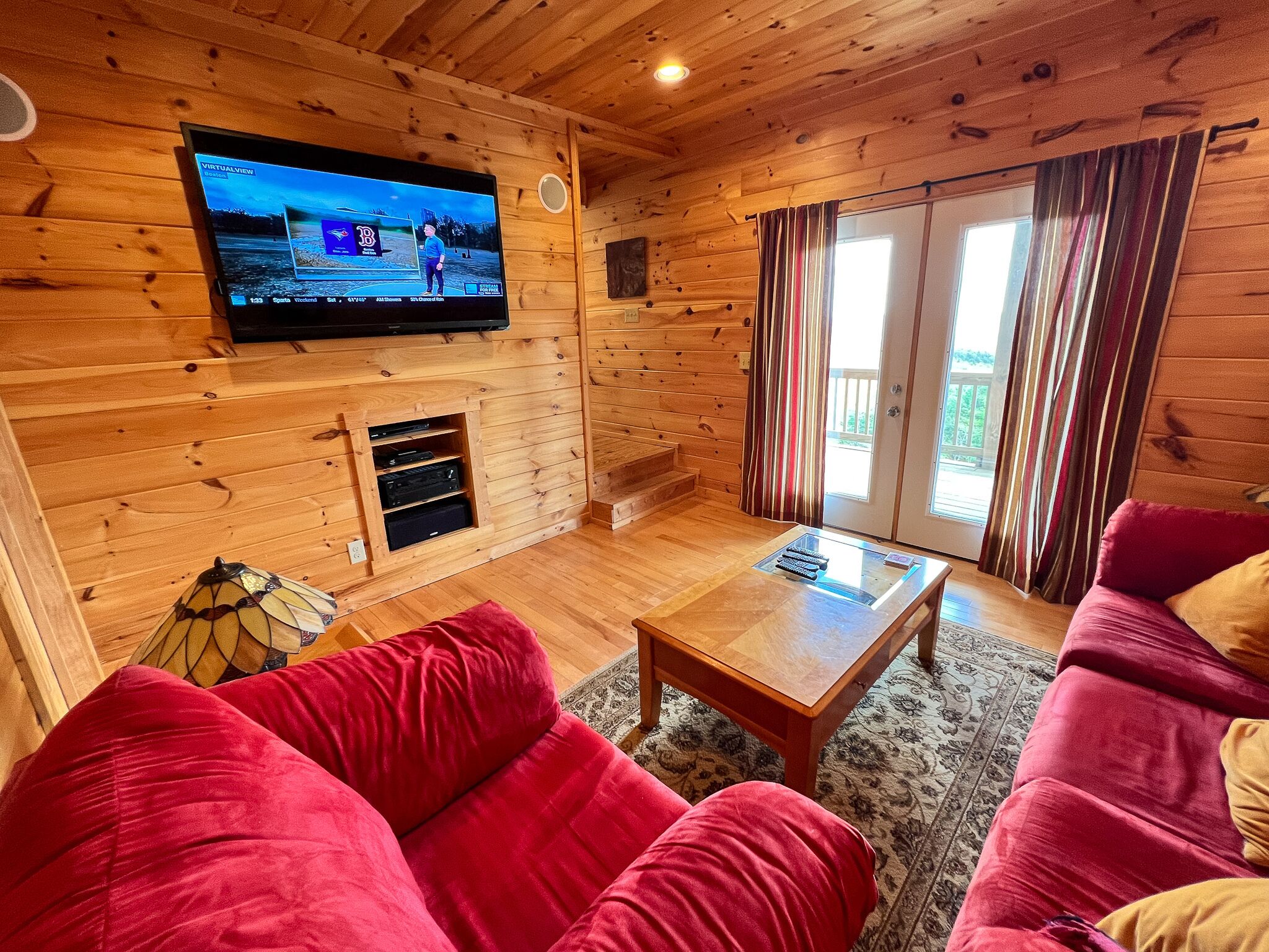 Un intérieur en bois avec un téléviseur fixé au mur, un canapé et une table basse.