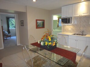A modern kitchen with white cabinets, a glass dining table with a red runner, and a flower centerpiece. - Xanadu 1 Suite - 2 bedroom Luxury on 11 private acres  (Cobble Hill)