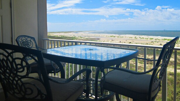 Un balcón con mesa y sillas con vistas a la playa.