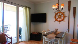 Un comedor con mesa, sillas, televisor y un adorno de timón.