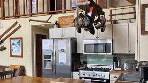 Een keuken met een houten kookeiland, roestvrijstalen apparatuur en een verhoogd eetgedeelte.