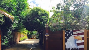 Un sendero conduce a una entrada con puerta de rejas, adornada con un mural de un águila y estrellas.