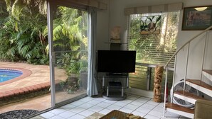 Una sala de estar con televisor, una piscina pequeña y una escalera.