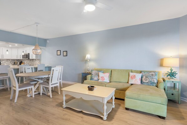 A modern living room with a dining area, a green sofa, and a white coffee table. - Casa Coastal East – Morning Sunrises, Evening Vibes, Island Home in Key West (Key West)