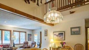 A dining area with a wooden table and chairs, a chandelier, and a view of the living room below. - Three bedroom townhouse, conveniently located (Killington)