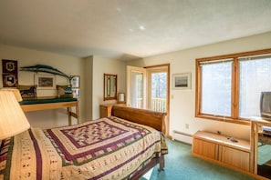 Ein Schlafzimmer mit Bett, Schreibtisch, Fernseher und einem Fenster mit Blick.