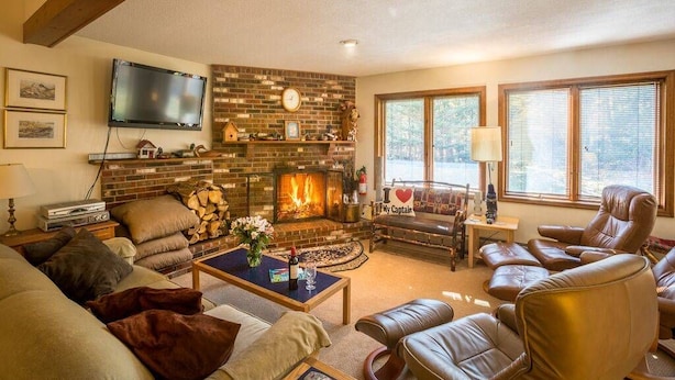 A cozy living room with a fireplace, leather chairs, a flat-screen TV, and a comfortable sofa. - Three bedroom townhouse, conveniently located (Killington)
