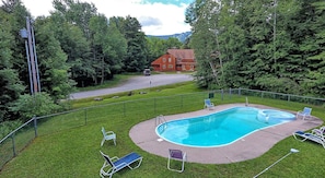Ein Swimmingpool mit umgebendem Zaun, Rasen und einigen Liegestühlen.
