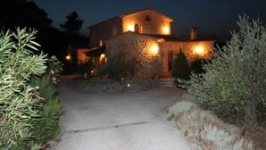 A stone building with a warm-lit entrance and a gravel pathway leading to it.