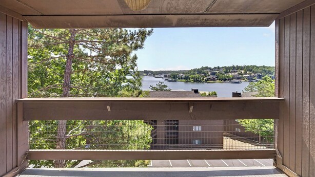 A balcony with a view of a lake and distant buildings. - Knolls 1122 - Two Bedroom Apartment, Sleeps 6 (Osage Beach,)