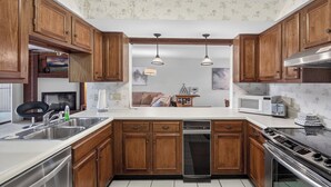 A kitchen with wooden cabinets, a stainless steel sink, a microwave, a toaster, and a stove. - Knolls 1122 - Two Bedroom Apartment, Sleeps 6 (Osage Beach,)