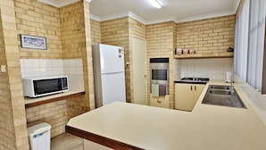 Una cocina con paredes de ladrillo, un refrigerador, un microondas, un horno, una estufa y un lavaplatos.