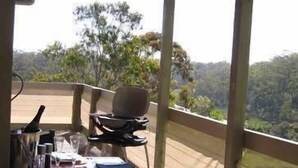 A dining table set for two with a view of a forested landscape.
