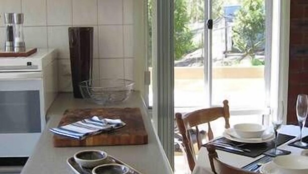 A kitchen with a dining area, featuring a large island with bowls, a coffee maker, and a glass container.
