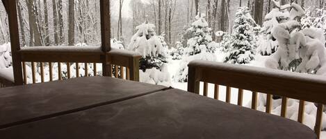 Een houten terras met een bankje, omringd door met sneeuw bedekte bomen.