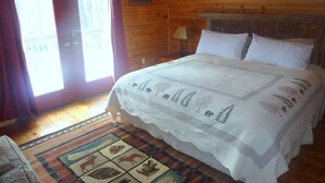A wooden cabin bedroom with a bed, a window, and a door. - Log Cabin with Private Outdoor Hot Tub (Hot Springs)