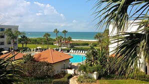 Un resort con piscina, palme e vista sull'oceano.