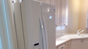 Eine Küche mit einem weißen Kühlschrank, Holzböden und weißen Schränken.