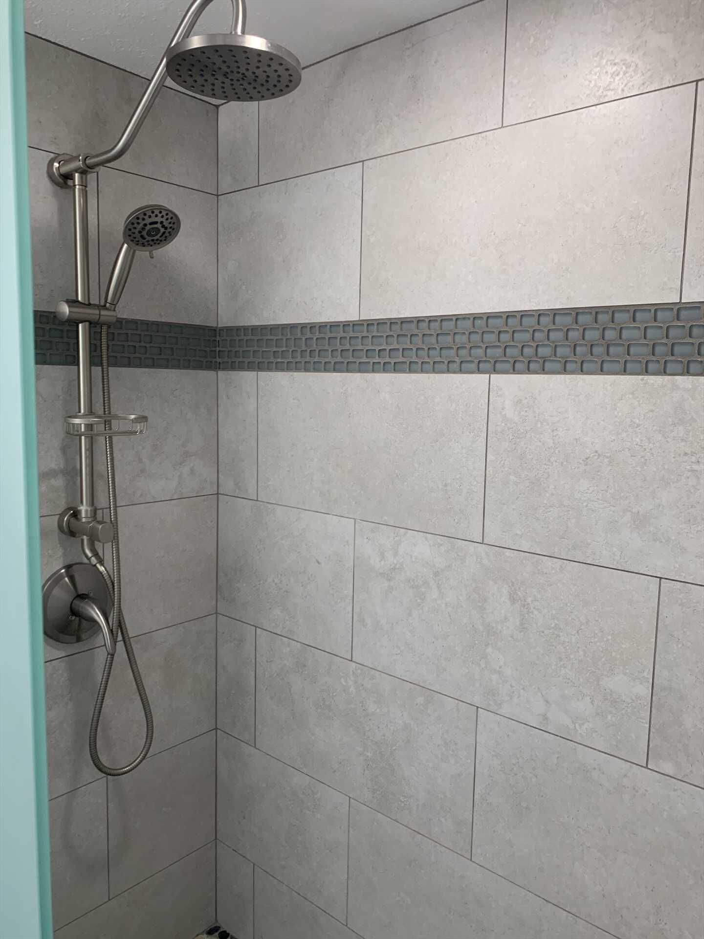 A shower with a handheld showerhead and a fixed showerhead, a handheld shower hose, and a wall-mounted control.