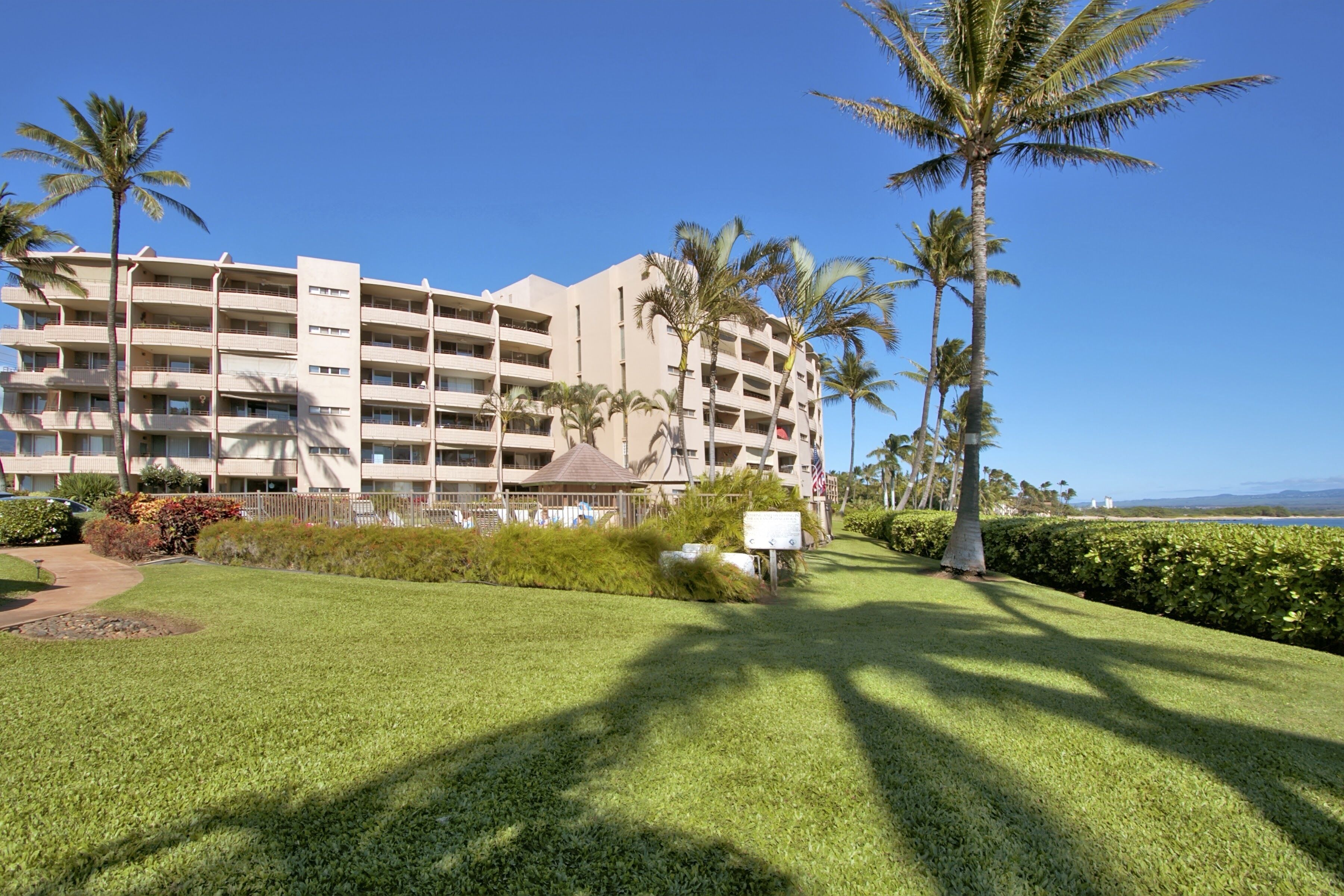 A multi-story hotel with a well-maintained lawn and palm trees.