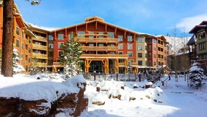 A multi-story hotel with a red facade, balconies, and a snow-covered landscape.