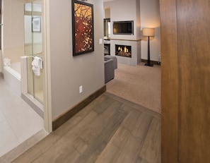 A hallway with a fireplace, a TV mounted on the wall, and a glass shower enclosure. - Charlie Rentz: Riverfront Resort/Spa, Ski-In/Out Penthouse, Ski Valet, Private Balcony #914 (Avon)