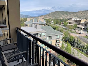 A balcony with a view of a cityscape, including buildings and a mountain range.