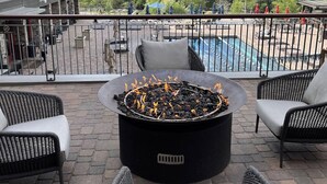 A terrace with a fire pit, outdoor seating, and a view of mountains.