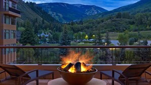 A balcony with a fire pit, overlooking a mountainous landscape.
