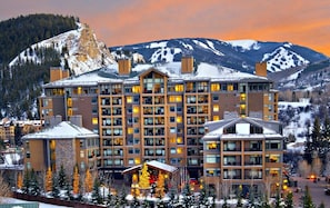 Ein mehrstöckiges Hotel mit einem zentralen Atrium, umgeben von schneebedeckten Bergen.