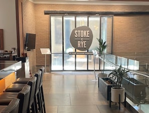 A restaurant interior with a sign reading 'STOKE & RYE' by Chef Richard Sandoval, a glass railing, and a potted plant. - Resort Ski In/Out Penthouse Studio/ Ski Valet (Avon)