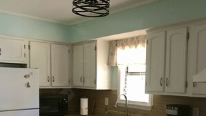 Cozinha com armários brancos, geladeira branca, micro-ondas, cafeteira e lava-louças.