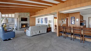 A spacious living area with a fireplace, seating, and a dining area with wooden chairs.