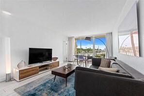 Relax in this stylish living room with a flat-screen TV, sofa, and dining area overlooking a city view.