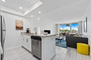 Enjoy meals in the spacious kitchen with a central island and dishwasher, adjacent to a dining area with a sofa and ottoman.