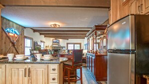 A spacious kitchen with wooden cabinets, a large island, and a stainless steel refrigerator.